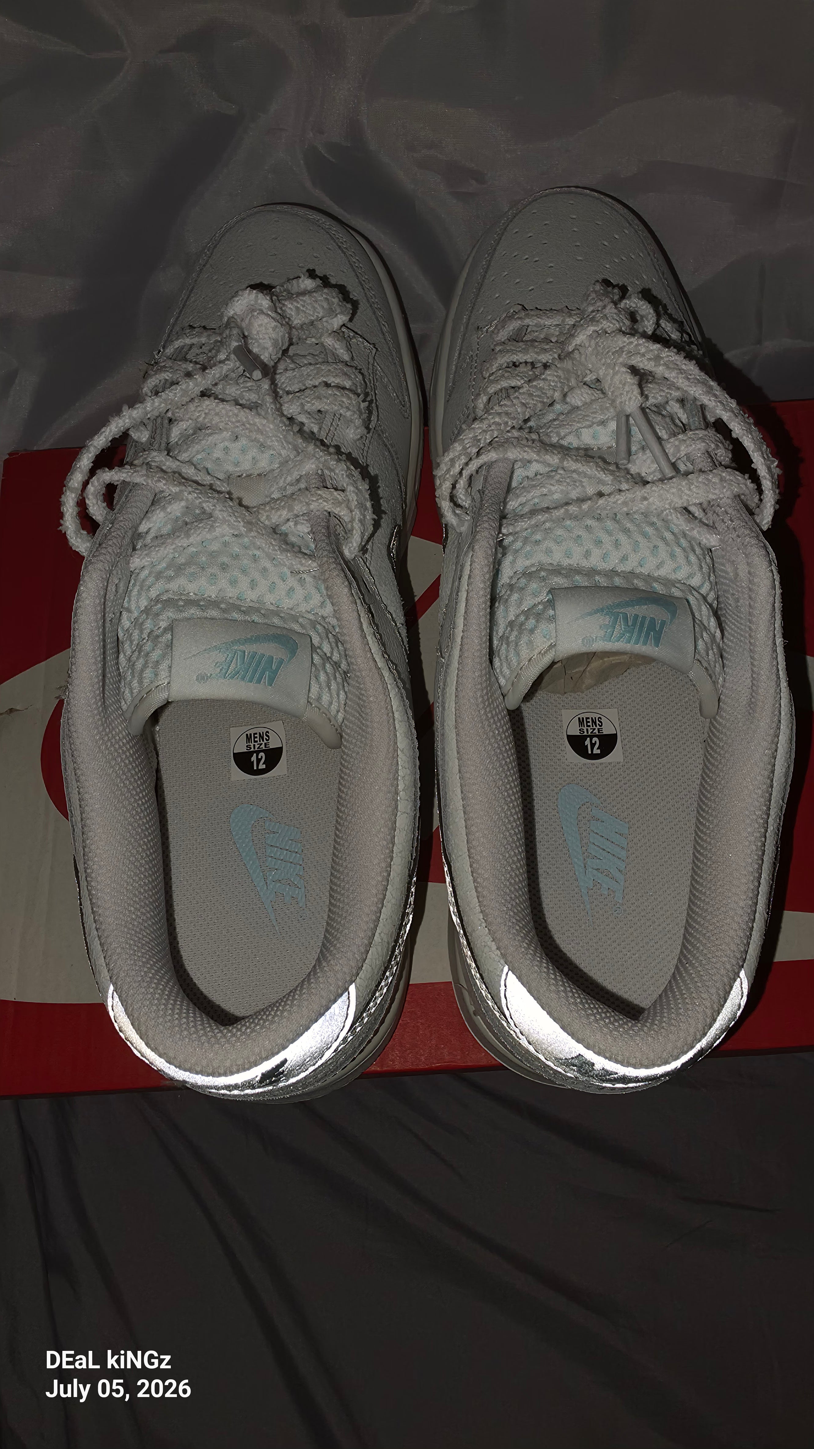 Nike Dunk Low SE "Winter Storm" sneakers, featuring a white textured upper and metallic silver reflective swooshes.