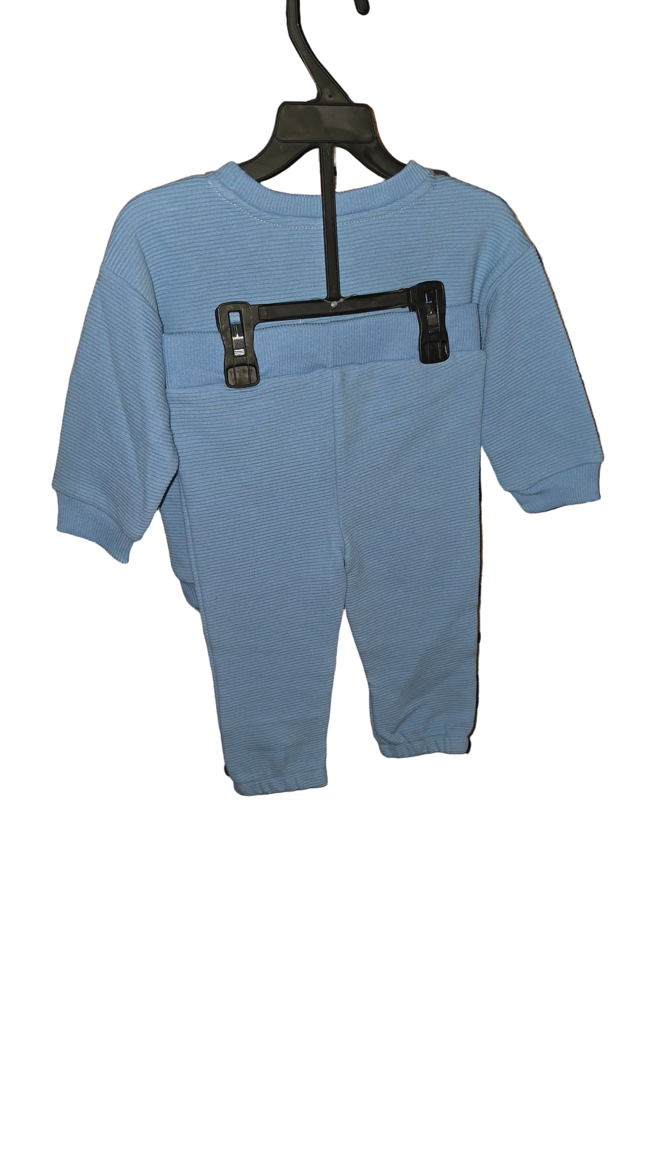 Blue children's outfit on a hanger against a black and brown patterned background