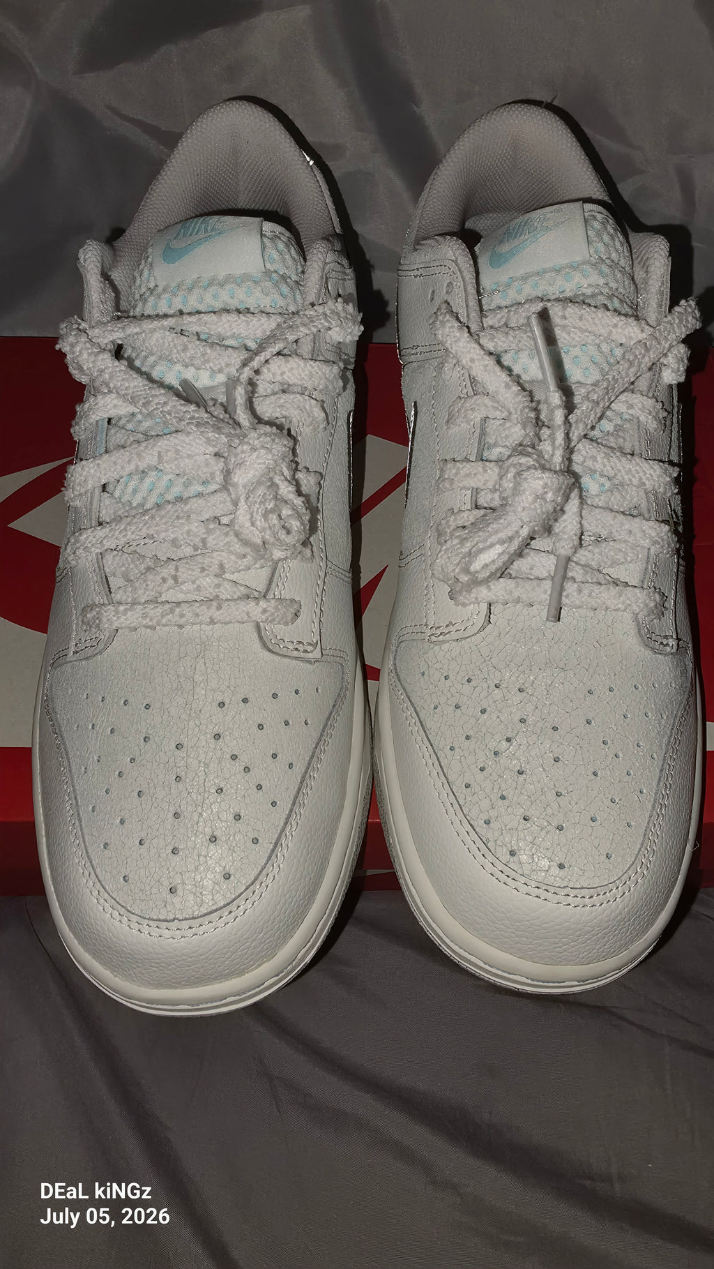Nike Dunk Low SE "Winter Storm" sneakers, featuring a white textured upper and metallic silver reflective swooshes.