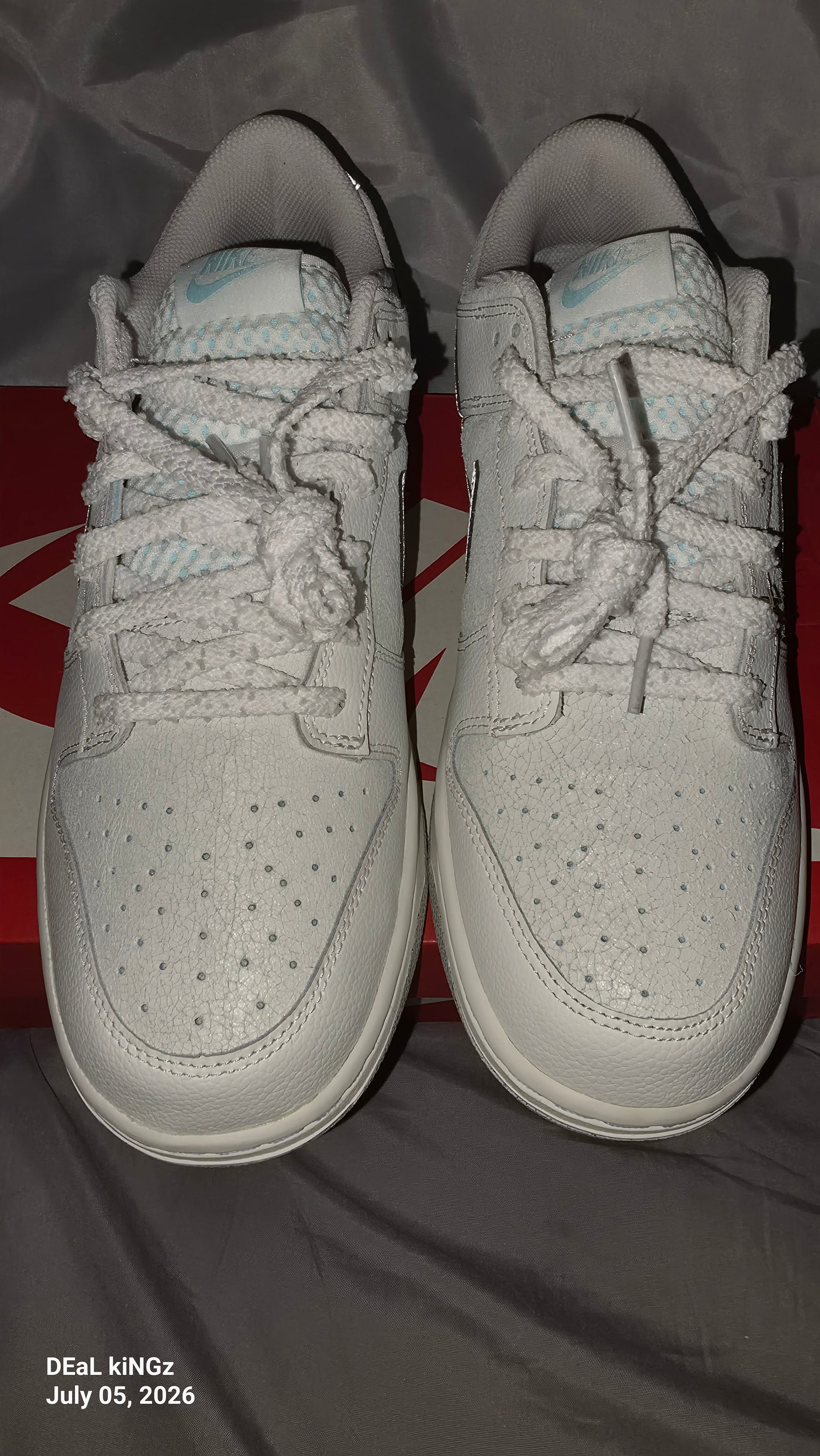 Nike Dunk Low SE "Winter Storm" sneakers, featuring a white textured upper and metallic silver reflective swooshes.