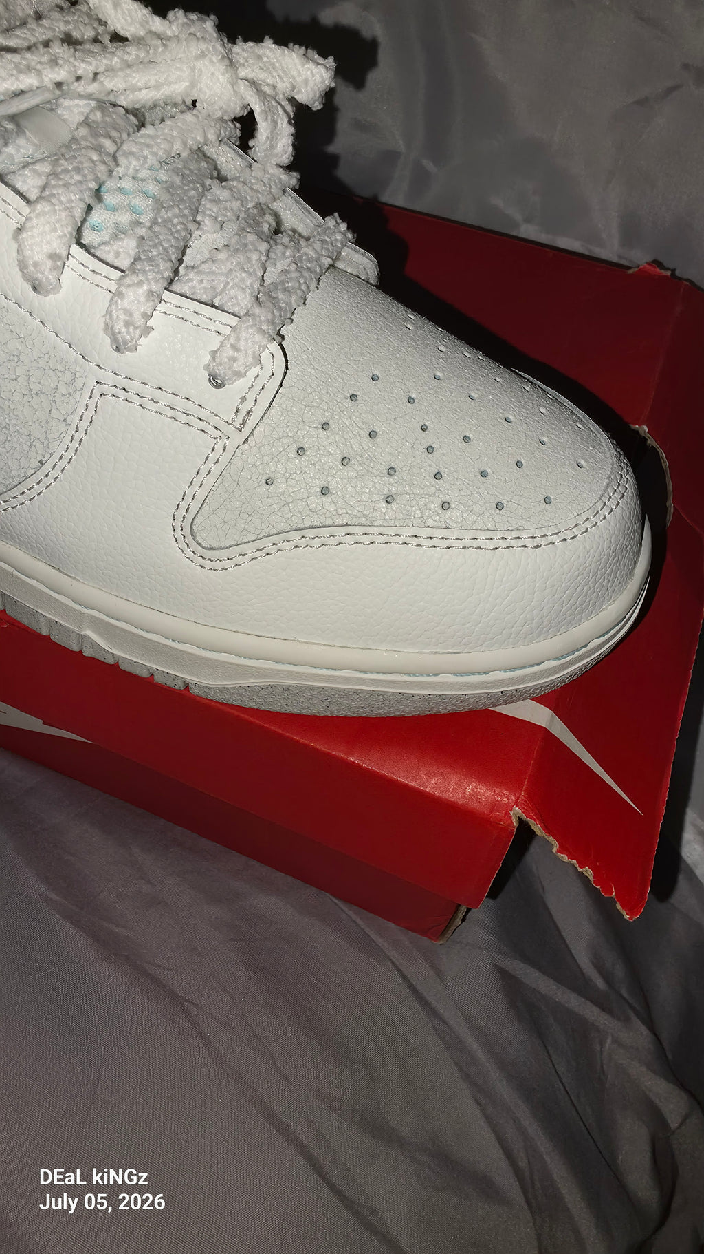 Nike Dunk Low SE "Winter Storm" sneakers, featuring a white textured upper and metallic silver reflective swooshes.