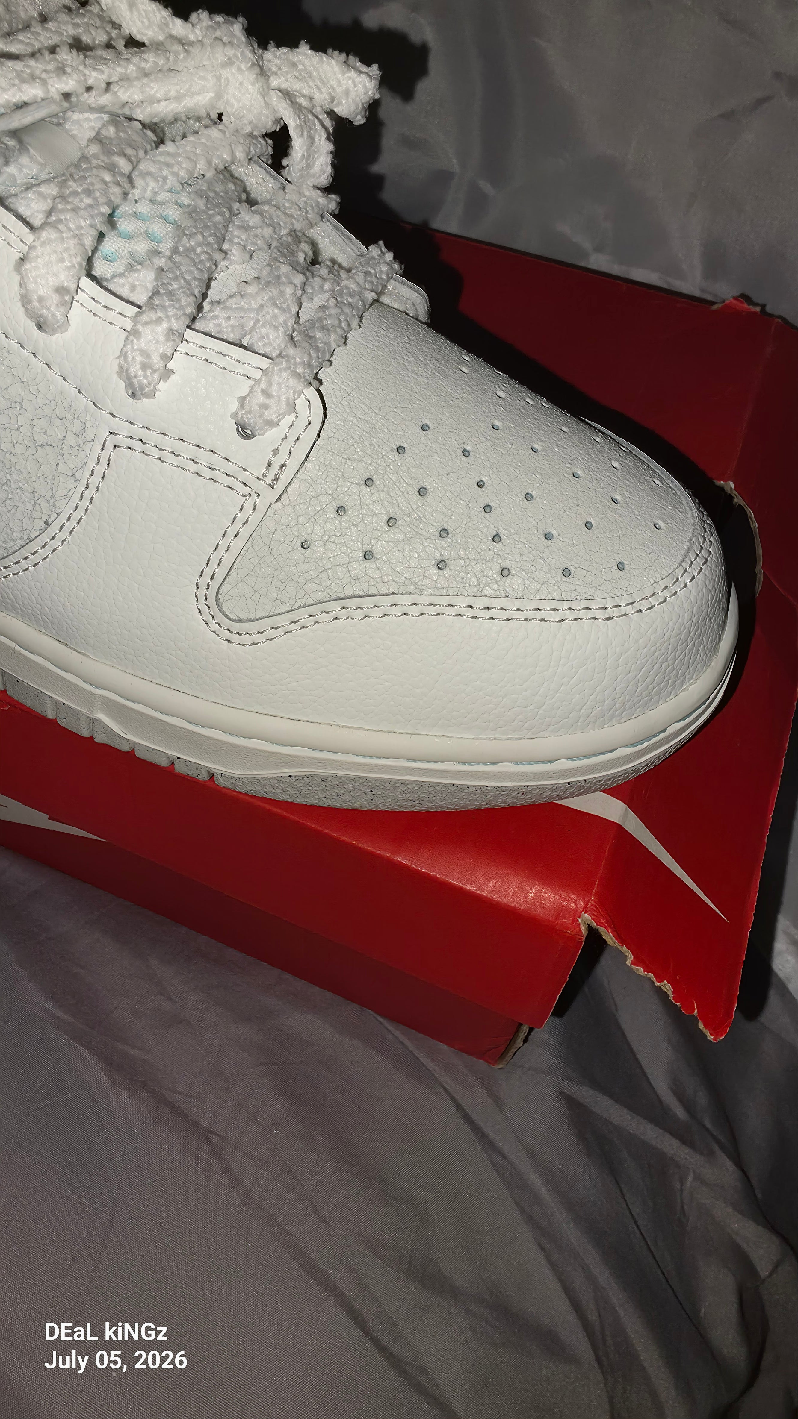 Nike Dunk Low SE "Winter Storm" sneakers, featuring a white textured upper and metallic silver reflective swooshes.