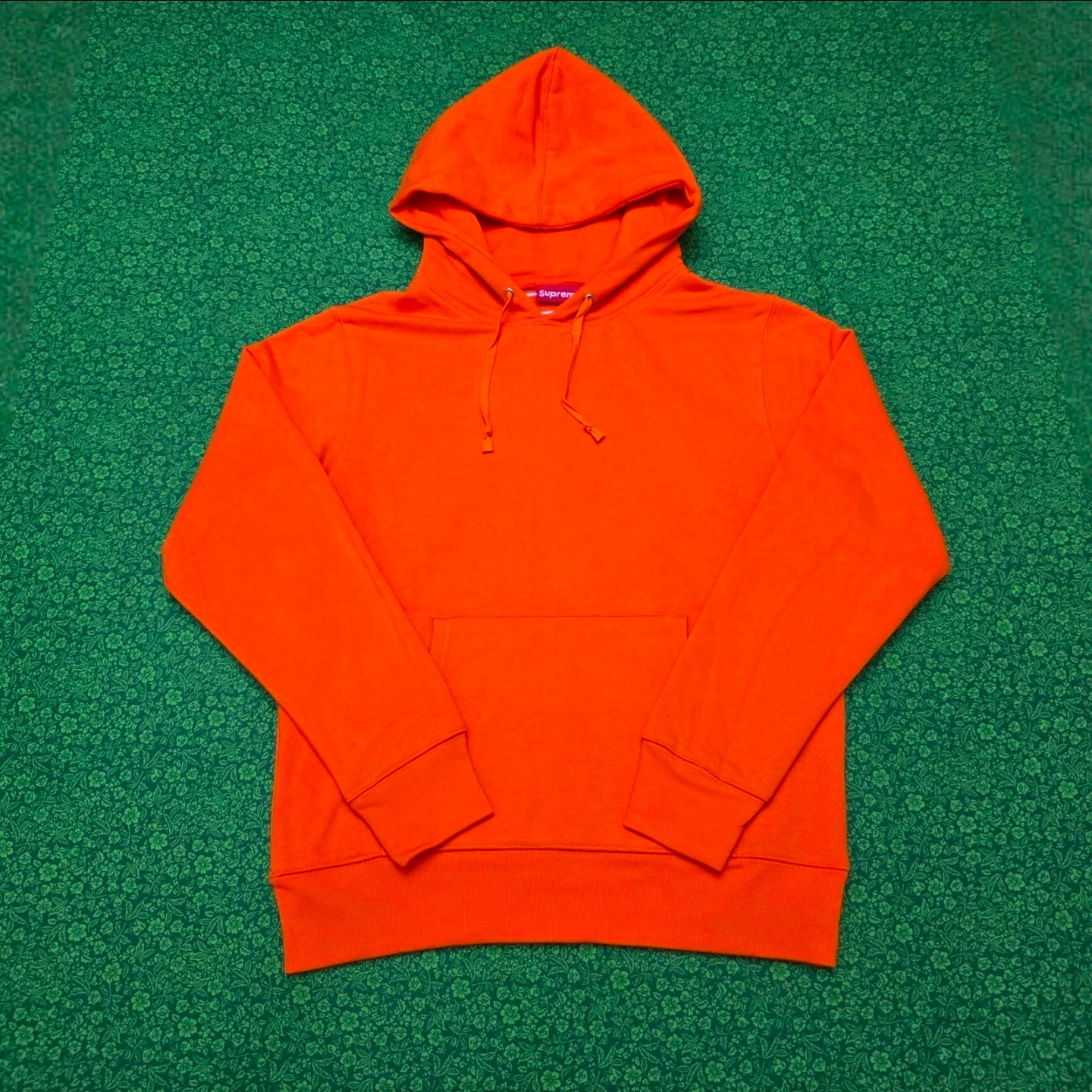 Supreme Satin Appliqué Hooded Sweatshirt in Bright Orange, featuring a large white satin logo running vertically down the back.