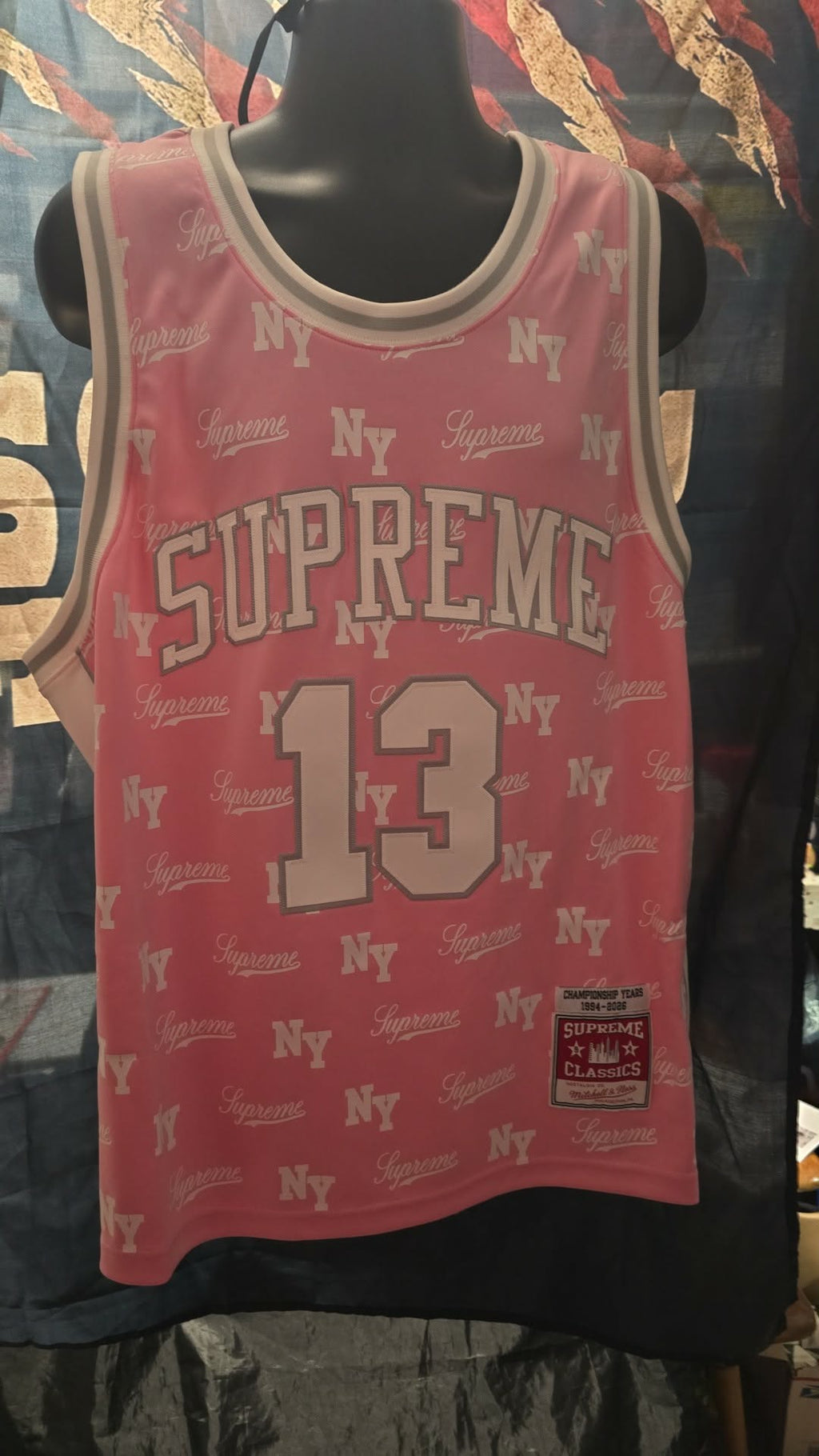 Pink Supreme x Mitchell & Ness monogram basketball jersey features tackle twill appliqué and a matching woven logo label at the lower front.Release Date: May 07, 2026