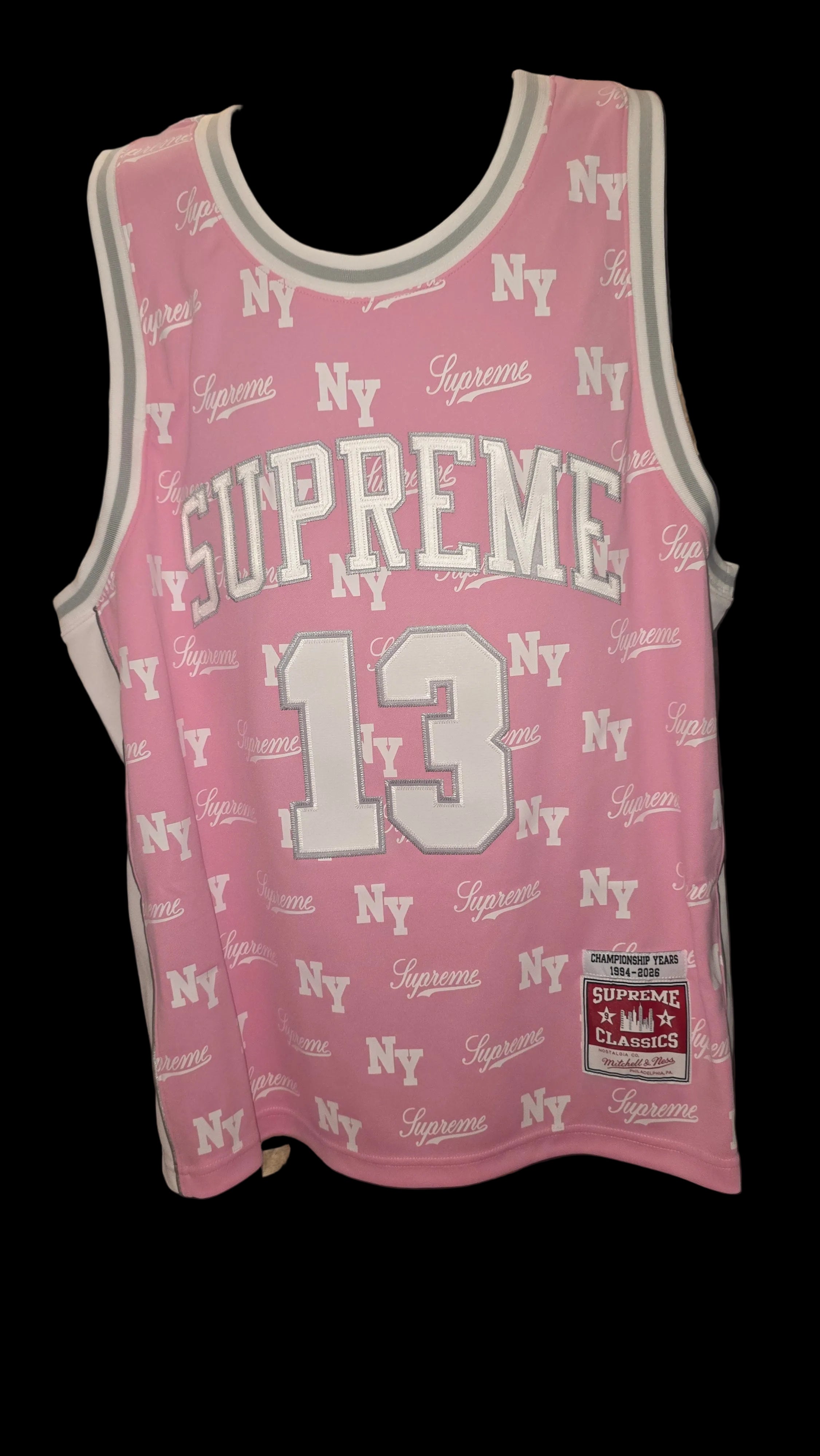 Pink Supreme x Mitchell & Ness monogram basketball jersey features tackle twill appliqué and a matching woven logo label at the lower front.Release Date: May 07, 2026