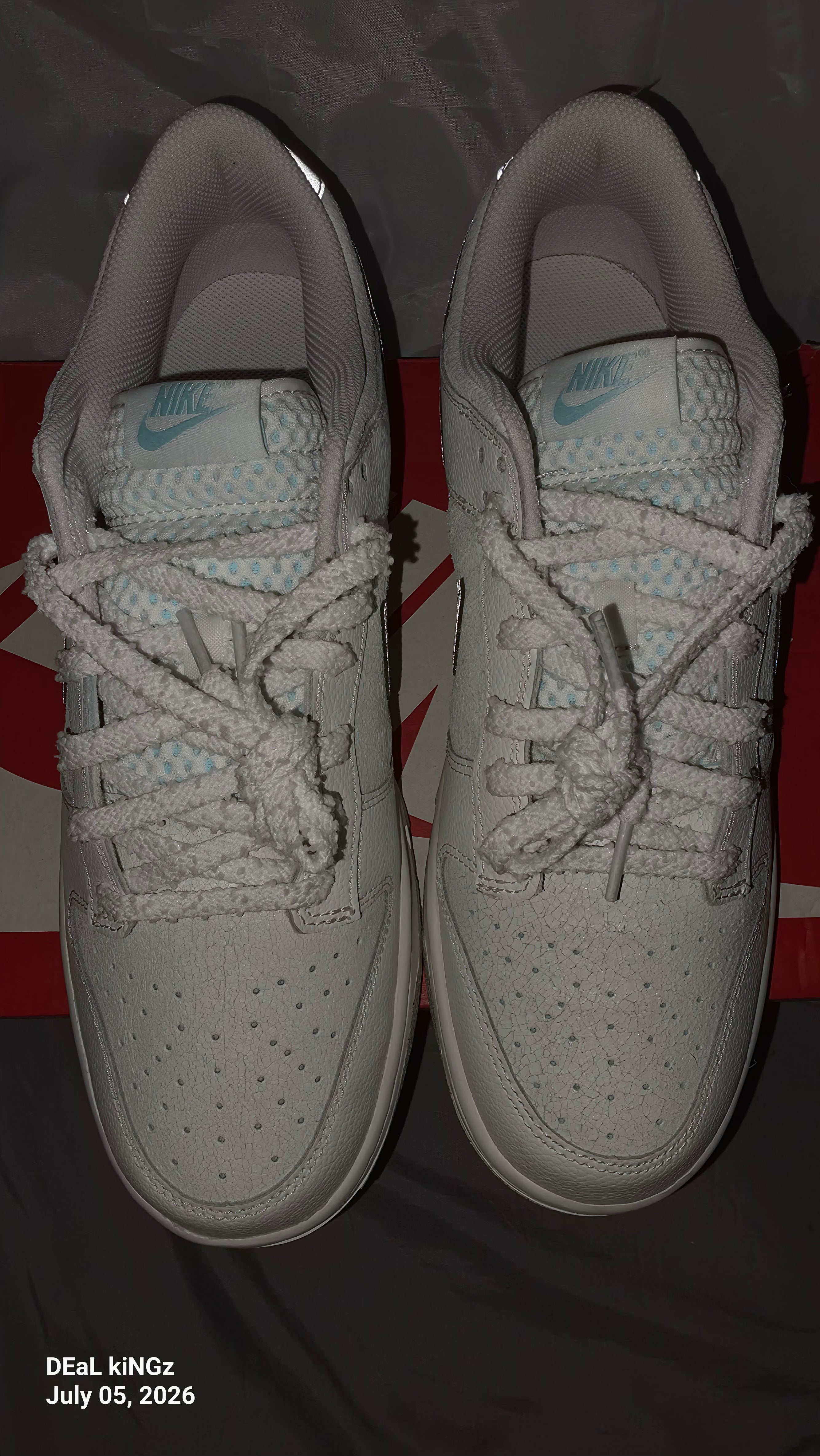 Nike Dunk Low SE "Winter Storm" sneakers, featuring a white textured upper and metallic silver reflective swooshes.