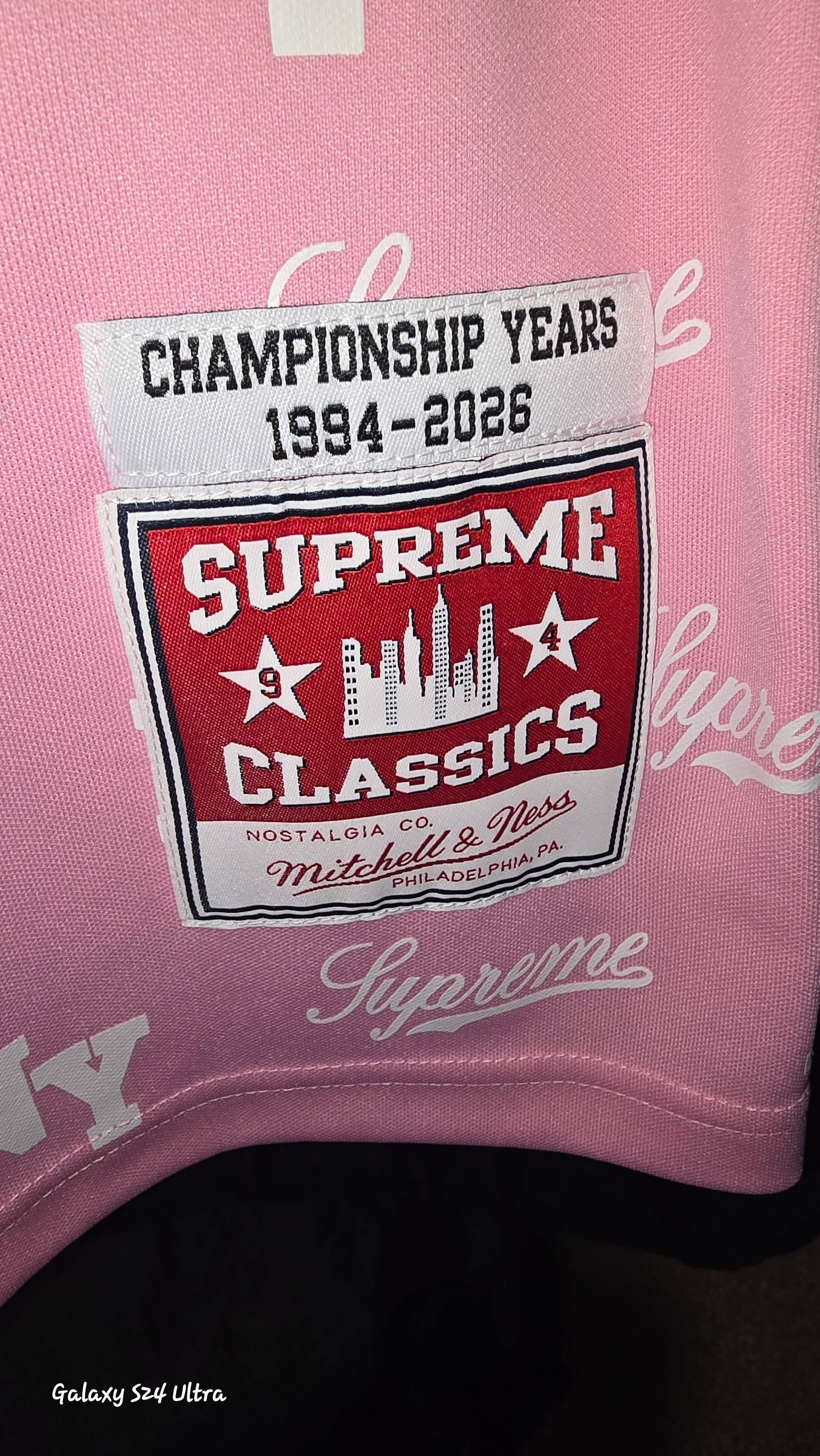 Pink Supreme x Mitchell & Ness monogram basketball jersey features tackle twill appliqué and a matching woven logo label at the lower front.Release Date: May 07, 2026