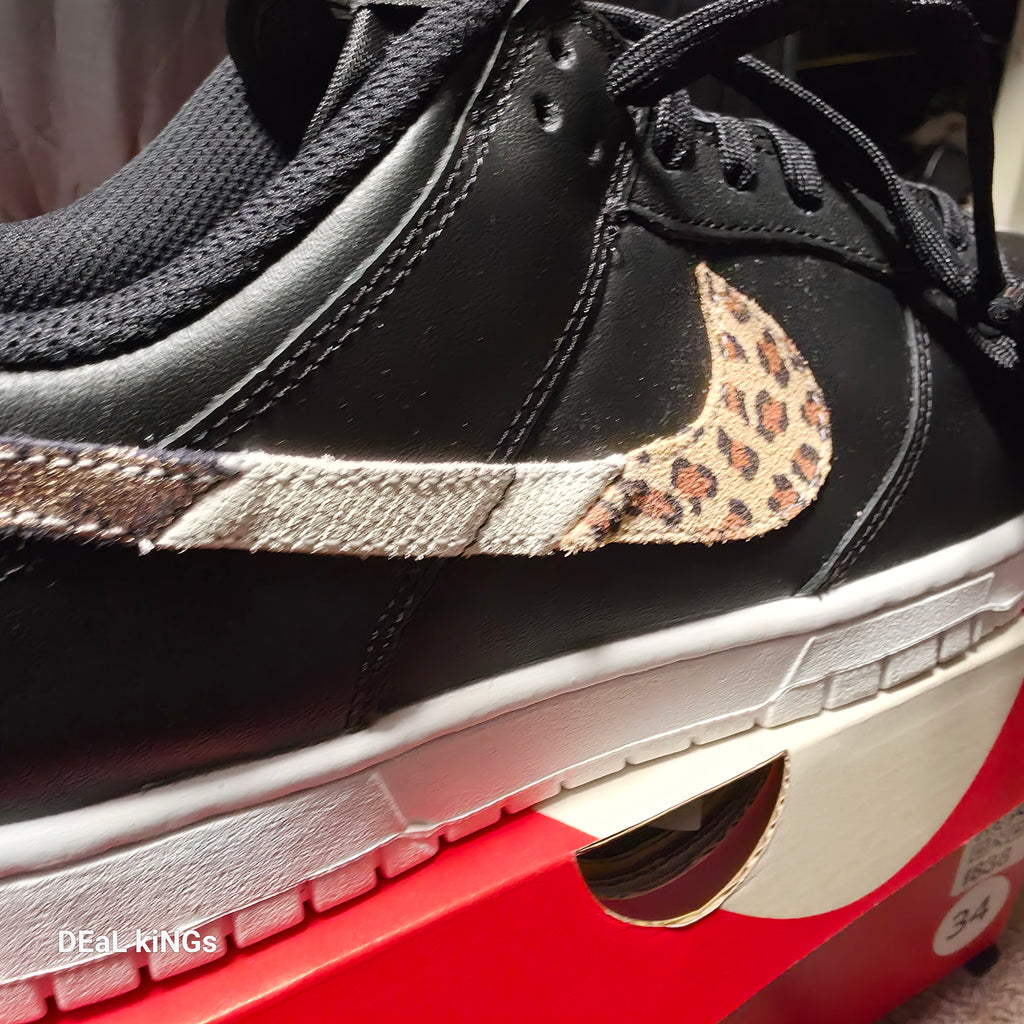 Nike Women's Dunk Low SE Primal sneakers feature a black leather upper with a distinctive animal print Swoosh.